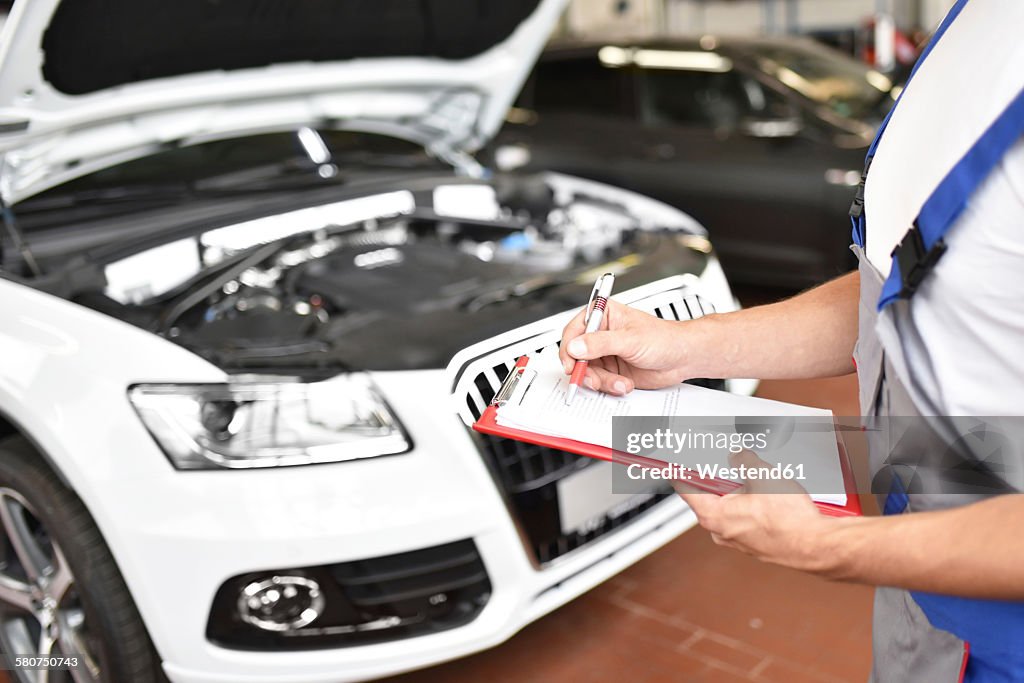 Car mechanic holding clipboard in a garage