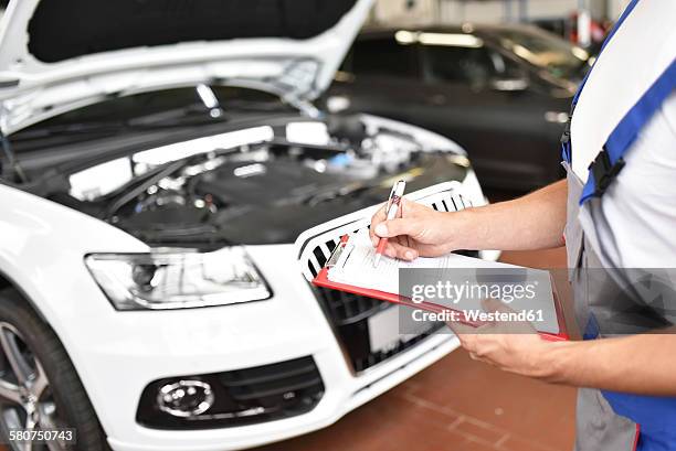 car mechanic holding clipboard in a garage - car review stock pictures, royalty-free photos & images