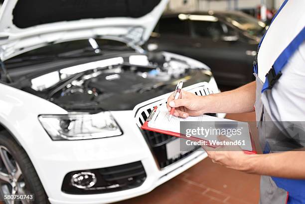 car mechanic holding clipboard in a garage - skill assessment stock pictures, royalty-free photos & images