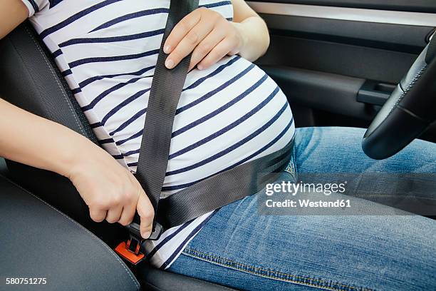 pregnant woman fastening safety belt in her car, close-up - pregnant woman car stock pictures, royalty-free photos & images
