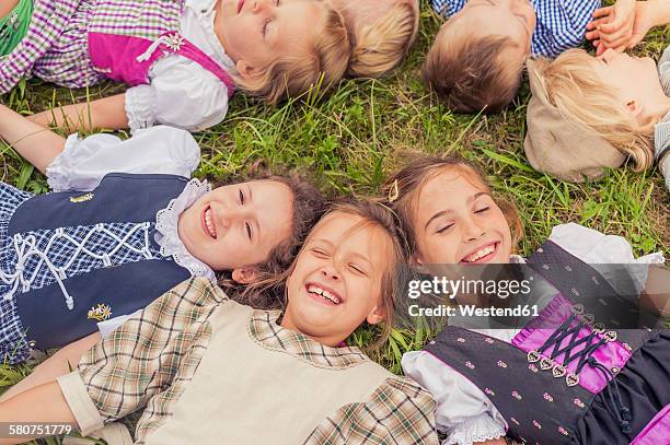 germany, saxony, group of children wearing traditional clothes lying on a meadow in circle - traditionelle kleidung stock-fotos und bilder