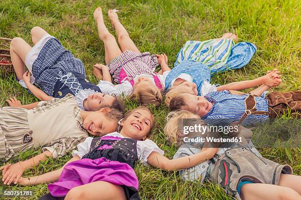 germany, saxony, group of children wearing traditional clothes lying on a meadow in circle - traditionelle kleidung stock-fotos und bilder
