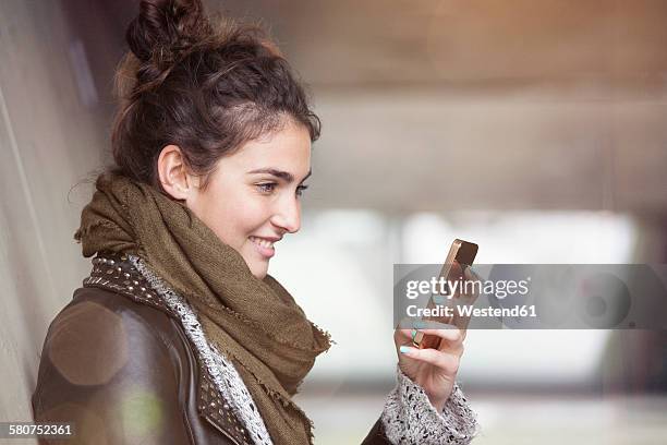 smiling young woman with smartphone - hair bun scarf woman stock pictures, royalty-free photos & images