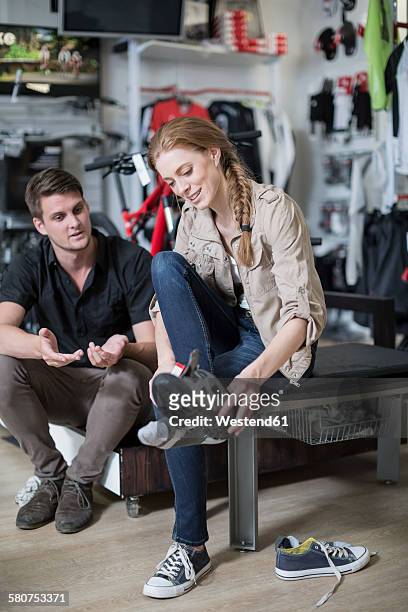 young woman buying bicycle shoes, salesman advising - sportswear shopping stockfoto's en -beelden