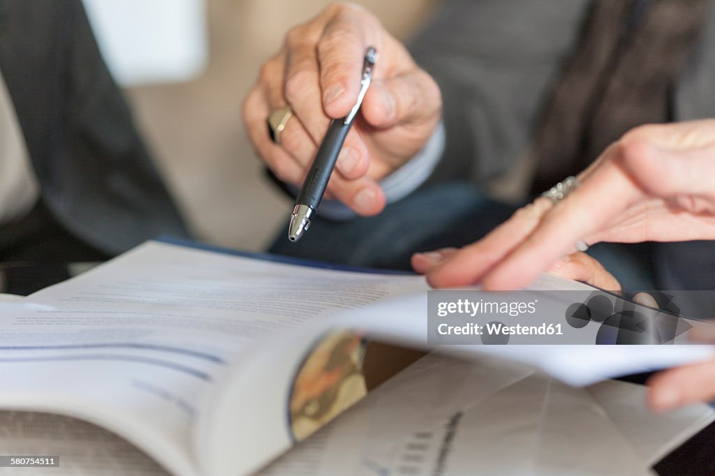 Hands holding booklet and ballpen, close-up