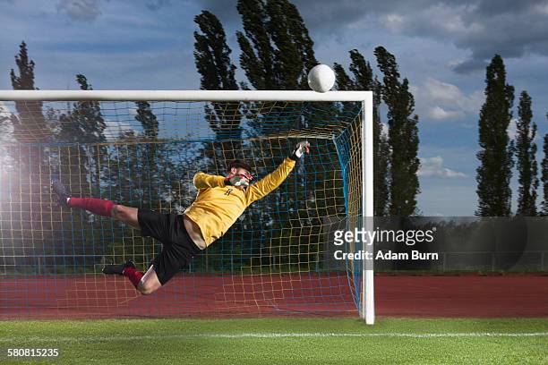 full length of soccer goalkeeper diving to block ball - trefferversuch stock-fotos und bilder