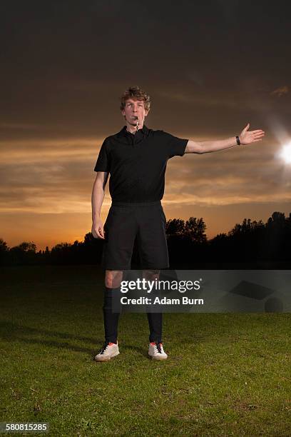 referee signaling while blowing whistle on soccer field - referee stock-fotos und bilder