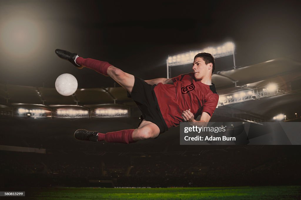Full length of soccer player kicking ball during match