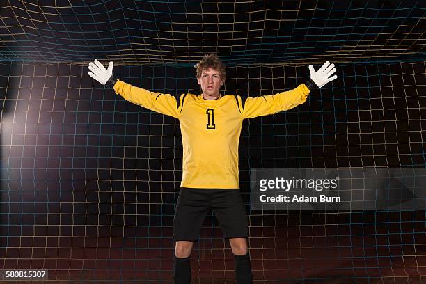 portrait of confident goalie defending soccer net on field - goalkeeper soccer stock-fotos und bilder