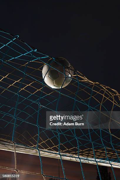 low angle view soccer ball in goal at night - scoring a goal stock-fotos und bilder