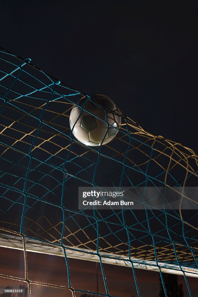 Low angle view soccer ball in goal at night