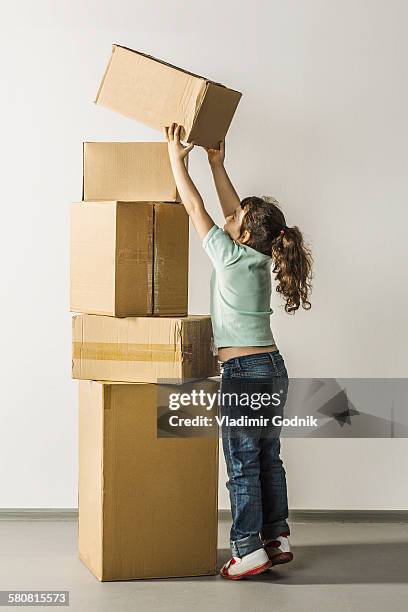 full length of girl stacking boxes in house - tiptoe imagens e fotografias de stock