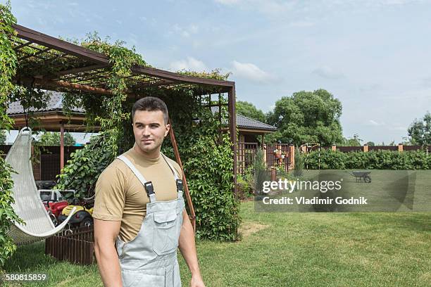 young man wearing bib overalls in backyard - bib overalls stockfoto's en -beelden