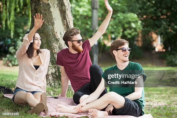 happy friends waving while relaxing at park - friends waving stock pictures, royalty-free photos & images