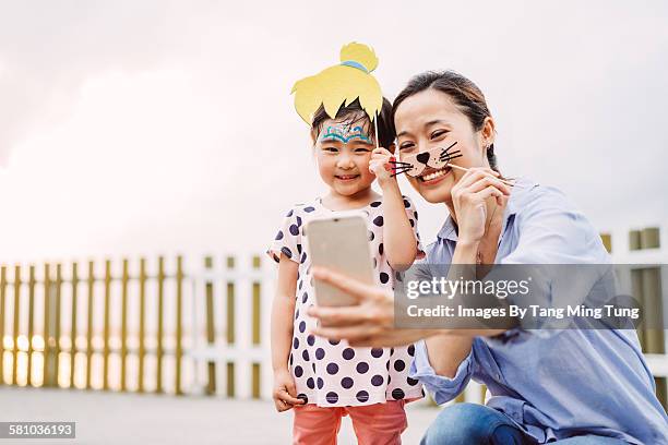 pretty mom & lovely little daughter taking selfie - funny mask stockfoto's en -beelden