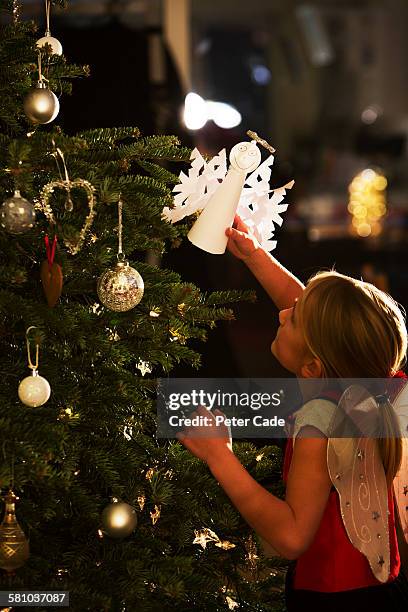 young girl putting angel on christmas tree - tree topper stock pictures, royalty-free photos & images
