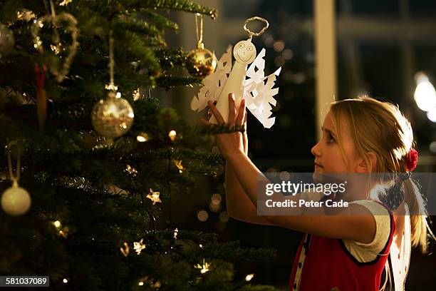 young girl putting angel on christmas tree - weihnachtsengel stock-fotos und bilder