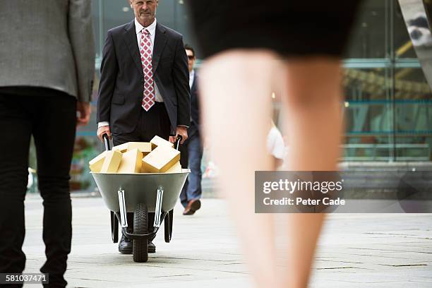 man pushing wheelbarrow full of gold blocks - 60 carat stock pictures, royalty-free photos & images