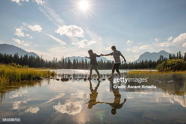 teenage couple cross lake on stepping stones - stepping stones stockfoto's en -beelden