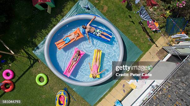 family in large padding pool in garden - プール　庭 ストックフォトと画像