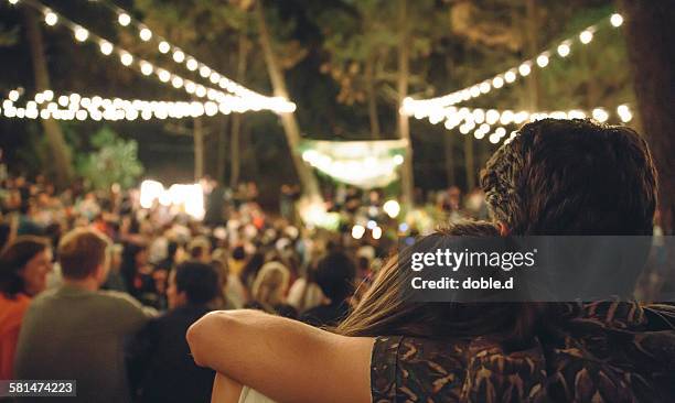 young couple embracing at night music festival - summer comedies party stockfoto's en -beelden