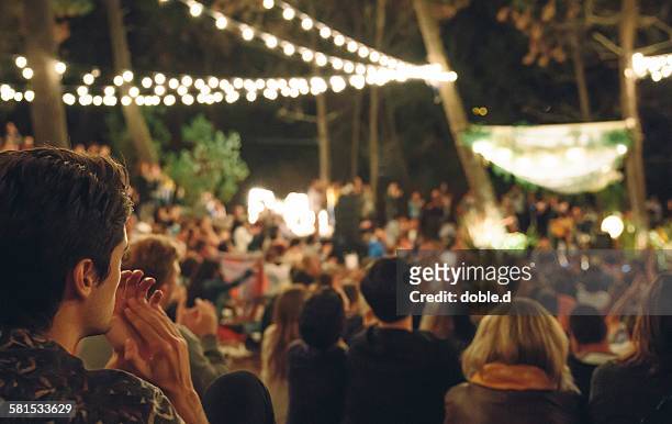 young man clapping in night music festival - concerto foto e immagini stock