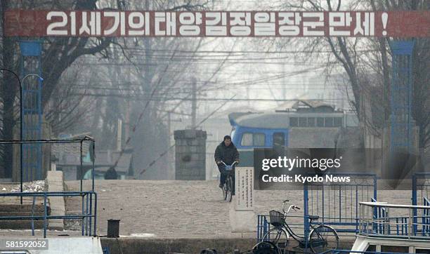 China - Photo taken from Dandong, China on the border with North Korea shows a cyclist near a propaganda banner for Kim Jong Il, the late North...