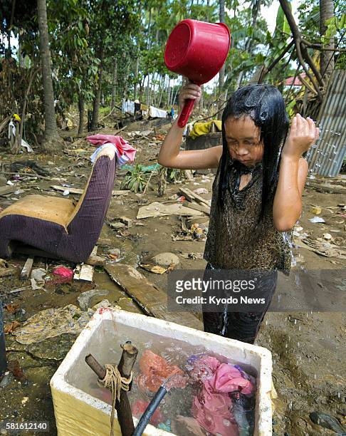 Philippines - A girl drenches herself with water in Cagayan de Oro on the Philippines' Mindanao island on Dec. 30 after the city was heavily damaged...