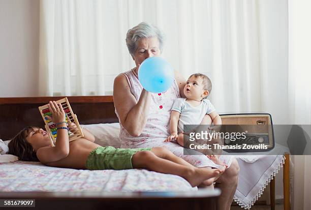 grandmother playing with grandsons - blowing up balloon stock pictures, royalty-free photos & images