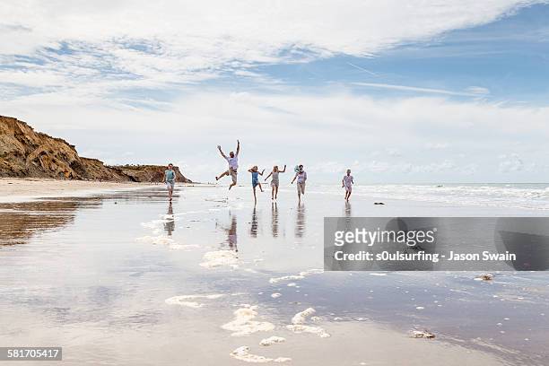 family running and jumping along the beach - s0ulsurfing stock pictures, royalty-free photos & images