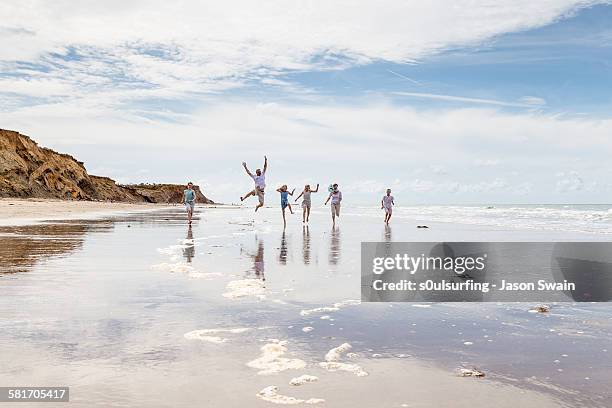 family running and jumping along the beach - isle of wight - fotografias e filmes do acervo