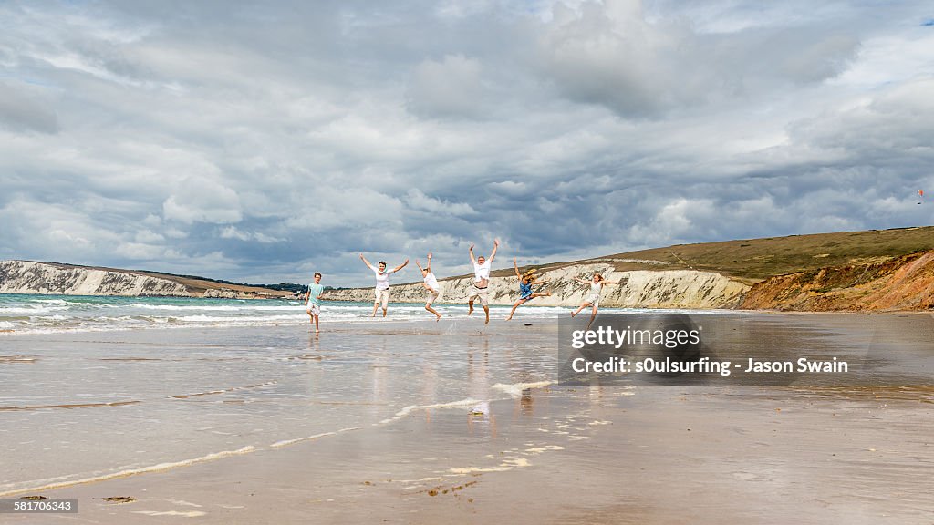 Family running and jumping along the beach