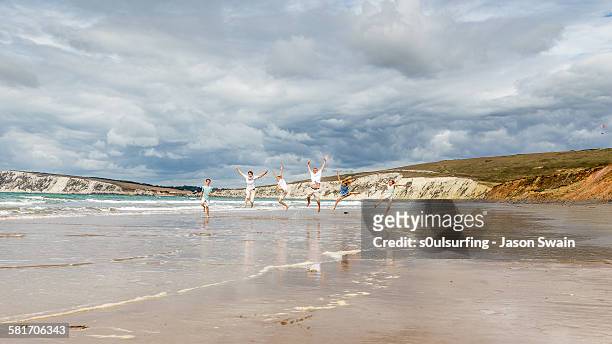 family running and jumping along the beach - isle of wight stock pictures, royalty-free photos & images