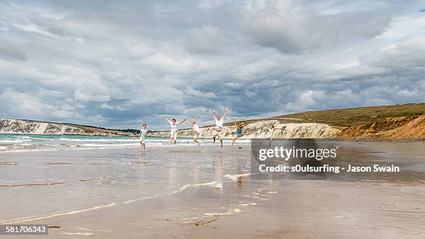 family running and jumping along the beach - freshwater bay isle of wight 個照片及圖片檔