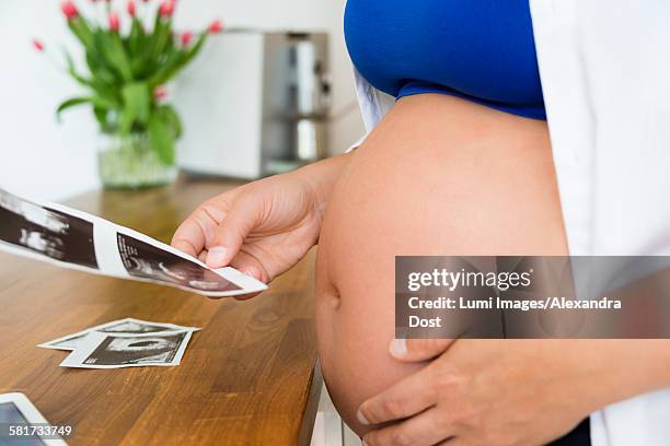 pregnant woman looking at ultrasound pictures - alexandra dost stockfoto's en -beelden