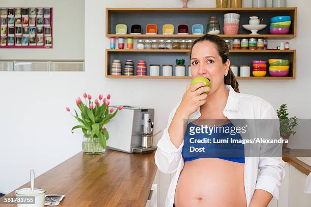 pregnant woman eating an apple - alexandra dost stock-fotos und bilder