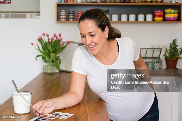 pregnant woman looking at ultrasound pictures - alexandra dost stockfoto's en -beelden
