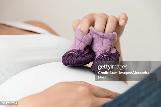 pregnant woman showing baby booties - alexandra dost stockfoto's en -beelden