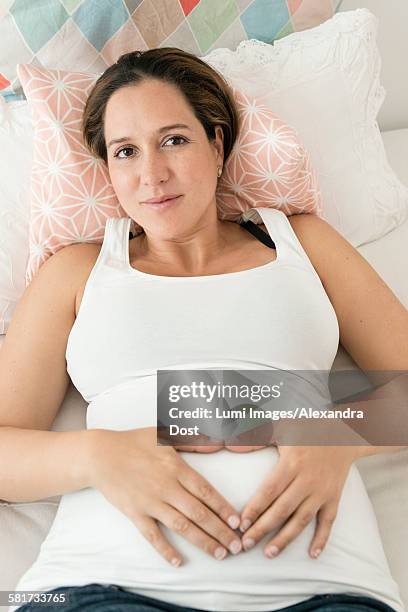 pregnant woman making heart shape on stomach - alexandra dost stockfoto's en -beelden