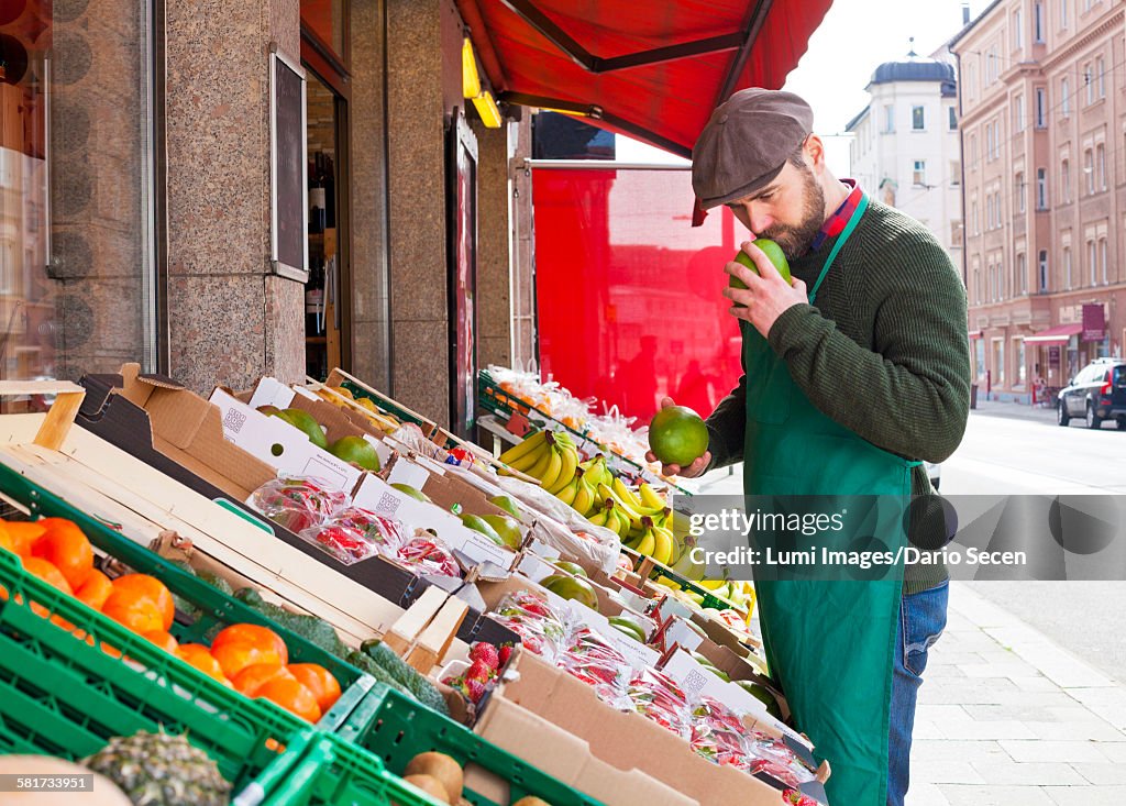 Greengrocers shop, grocer smelling fruit