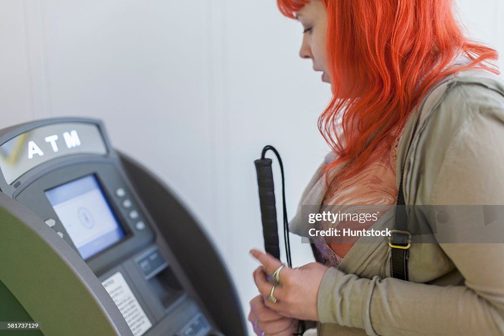 Young blind woman using a bank ATM