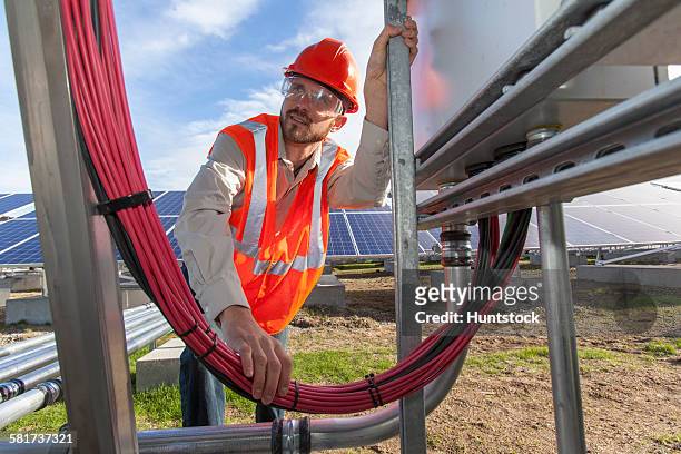 solar photovoltaic installer working on power connections for a pv array - cable installer stock pictures, royalty-free photos & images