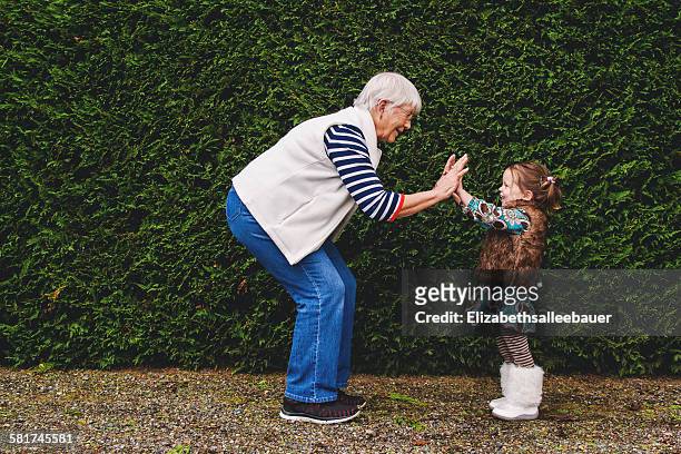 girl playing pat-a-cake with her grandmother - granddaughter stock pictures, royalty-free photos & images