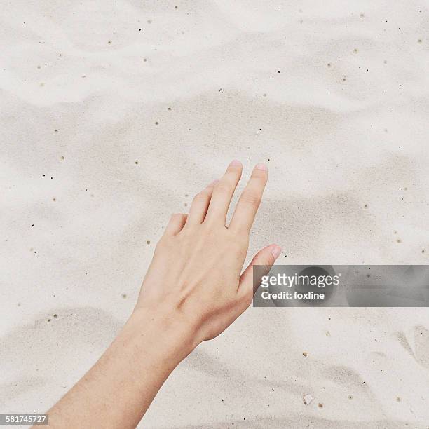 close-up of hand reaching for sand on the beach - estirar fotografías e imágenes de stock