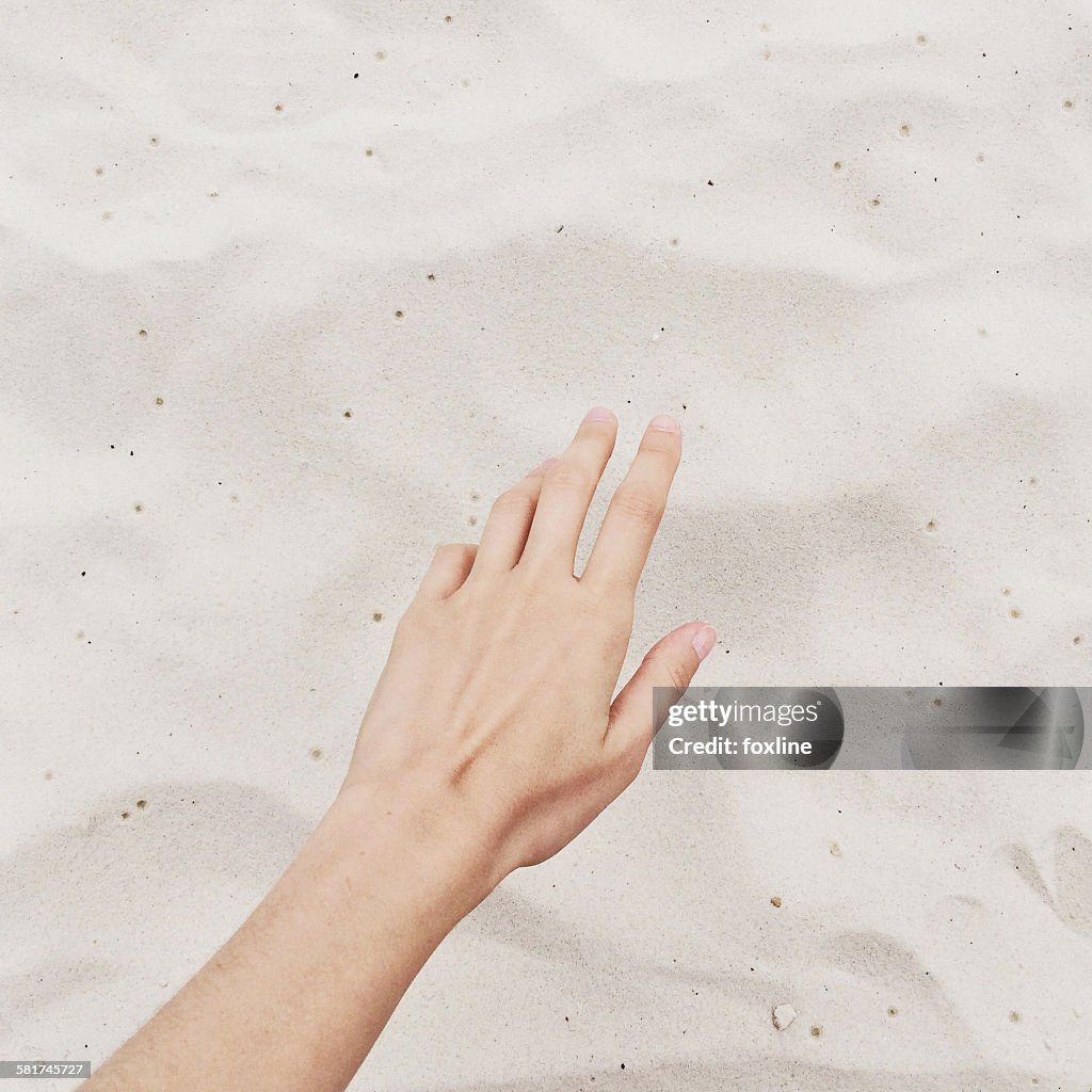 Close-up of hand reaching for sand on the beach