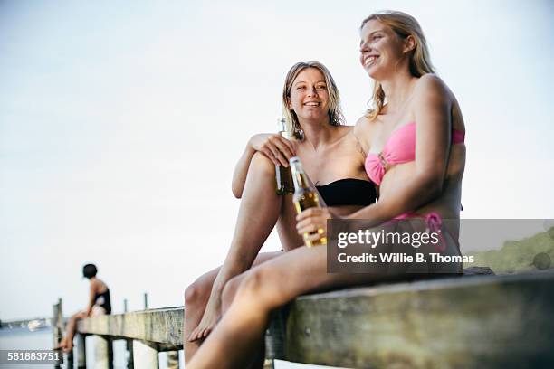 young women relaxing by lake with beers - long jetty stock pictures, royalty-free photos & images