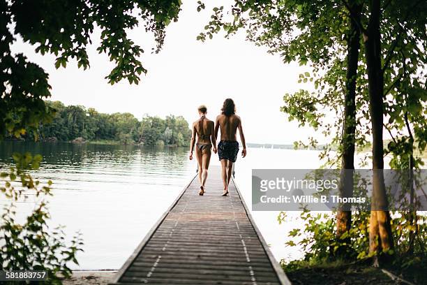 caucasian couple walking on wooden dock over lake - steg zwei menschen stock-fotos und bilder