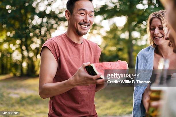 young man with watermelon at cookout - watermelon picnic stock pictures, royalty-free photos & images