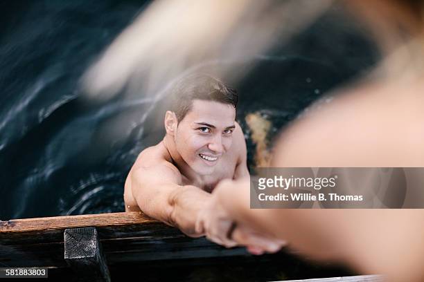 young man climbing onto pier - support stock-fotos und bilder
