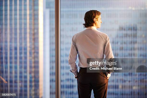 business man looking at sun from city apartment - sun city center stock pictures, royalty-free photos & images